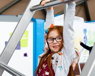 A child tests their grip endurance on our hang time exhibit