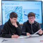 School pupils looking at a map and flight plan in a classroom