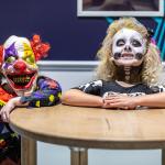 Two young people in Halloween costumes appear as having no bodies at a 'head on a plate' illusion