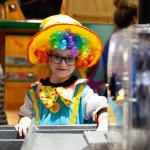 A young person dressed as a scary clown plays at a water table