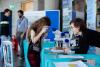 A visitor looks at an object through a microscope, guided by an expert