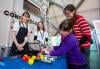 Visitors try using a prosthetic arm and hand to pick up coloured balls from the surface of a table