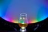 A glass of whisky against the backdrop of the Planetarium. Coloured lighting illuminates the domed ceiling. Text on the glass reads, 'The Good Spirits Company'.