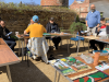 a group of people sit outside whilst creating their art