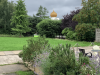 The green shrubbery and trees of the hidden gardens, the gurdwara is in the distance