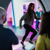 Two people watch a third person running on the hamster wheel