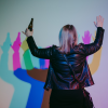 A person is dancing with a bottle of beer in front of our rainbow light exhibit