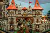 LEGO medieval castle gate with red-roofed towers, knights, a mounted rider and minifigures on the battlements